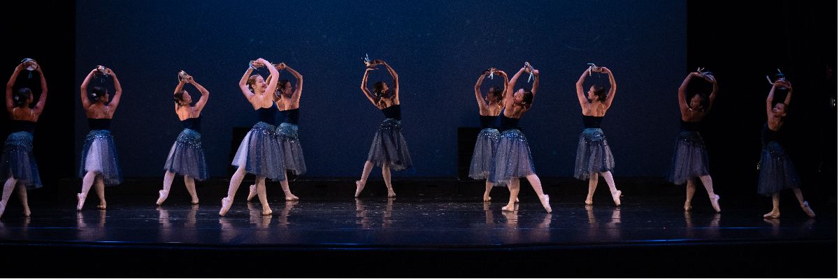 FVAD ballet students on stage in dark blue tutu dresses and holding tambourines.