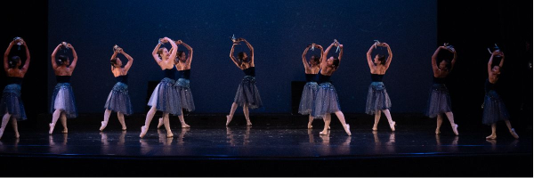 FVAD ballet students on stage in dark blue tutu dresses and holding tambourines.