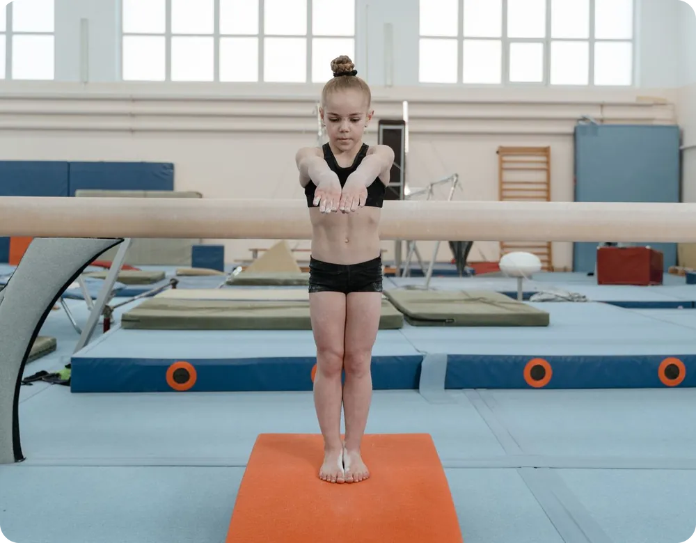 Young gymnast training at the balance beam in a gymnastics club